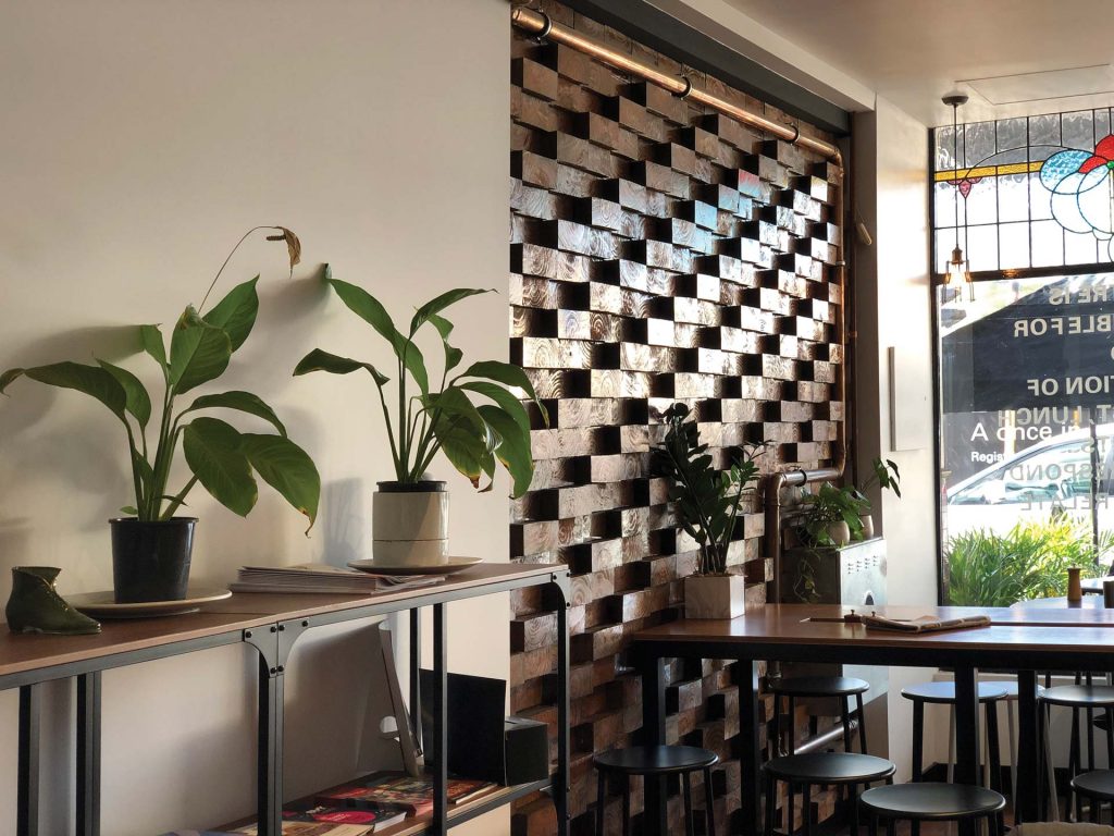 Trendy café filled with bar tables and stools with lots of indoor plants