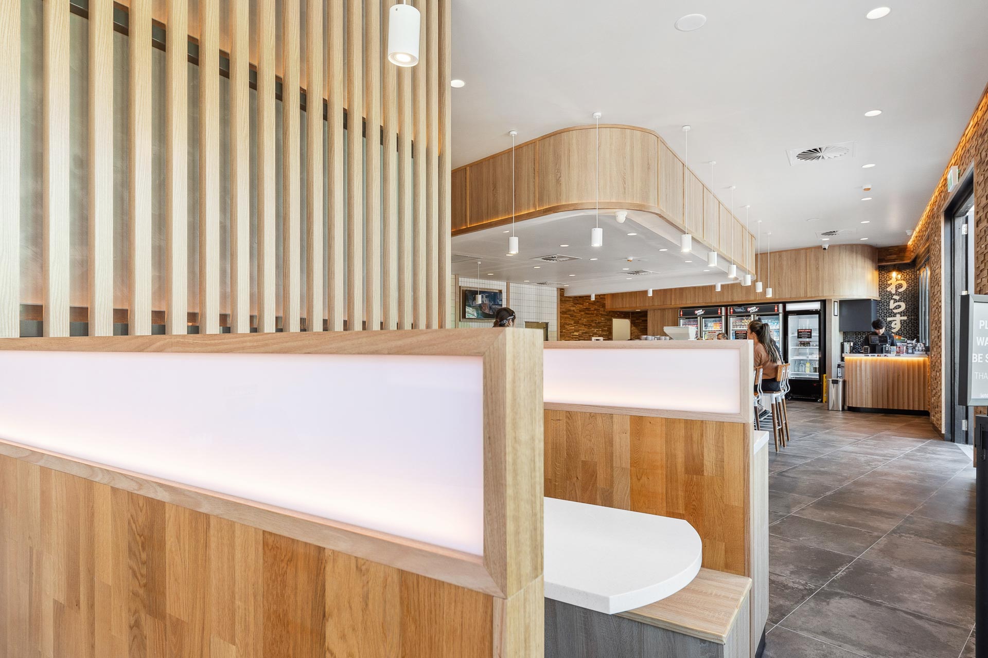 The interior fitout of Wara Sushi in Rockingham, featuring wooden seating booths and wooden screening.