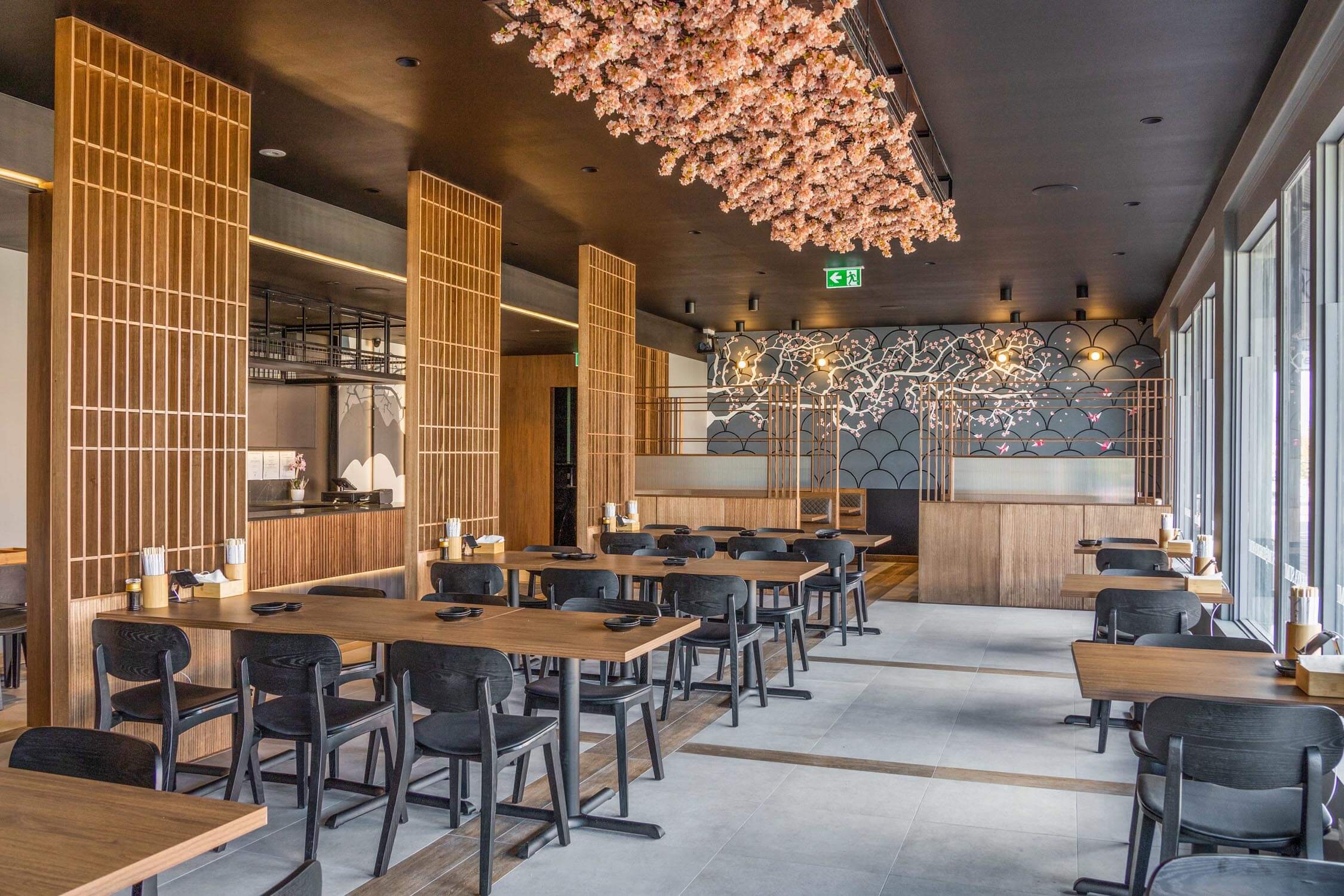 A restaurant with dark walls, wooden tables, wooden wall panels and a floral hanging centre-piece that was achieved by following a commercial design guide.